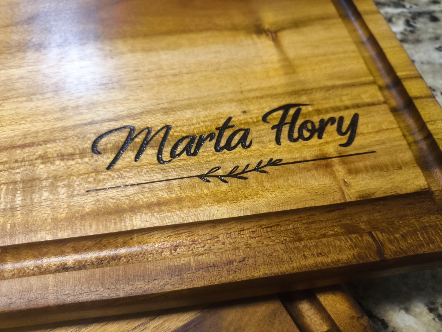 Tabla de madera con un nombre grabado en letra cursiva